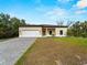 Charming single-story home featuring a paved driveway and attached two-car garage, set against a bright blue sky at 3376 Dunbar St, Port Charlotte, FL 33948