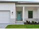 A modern home welcomes visitors with a turquoise front door, framed by a covered entrance and manicured landscaping at 4081 Felhorn St, Port Charlotte, FL 33948