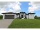 Beautiful, modern single-Gathering home with a lush green lawn, paved driveway, and a two-car garage at 8124 Welsford Rd, Port Charlotte, FL 33981