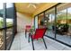 Relaxing screened-in patio with a glass table and two red chairs with sliding glass doors at 5685 Ashton Lake Dr # 2, Sarasota, FL 34231