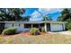 Charming single-story home featuring an attached garage, manicured mulch beds, and mature trees at 18300 Troon Ave, Port Charlotte, FL 33948