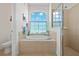 Spa-like bathroom with a soaking tub, walk-in shower, and large window at 24449 Manchester Trl, Punta Gorda, FL 33980