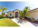 Tan house with palm trees, screened entryway, and landscaped yard at 16446 Belo Ct, Punta Gorda, FL 33955