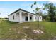 View of the backyard with covered patio and a slender tree at 2049 Delta St, Port Charlotte, FL 33952