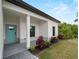 Charming front entrance with a covered porch, blue door, and landscaped garden bed at 2049 Delta St, Port Charlotte, FL 33952