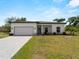 Charming single-story home showcasing a paved driveway, attached garage, and a well-kept lawn at 2049 Delta St, Port Charlotte, FL 33952