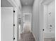 Hallway featuring neutral gray walls and gray wood-look tiling with white trim on the doorways at 2049 Delta St, Port Charlotte, FL 33952