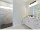 Modern bathroom featuring a vanity with white cabinets and a walk-in shower with marble-look tile at 13348 Rayburn Ln, Port Charlotte, FL 33981