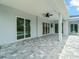 Covered outdoor lanai with brick pavers and ceiling fan with multiple sliding glass door entrances at 13348 Rayburn Ln, Port Charlotte, FL 33981