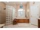 Spa-like bathroom with glass block shower, built-in soaking tub, and wood vanity at 437 Madrid Blvd, Punta Gorda, FL 33950