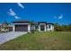 Move-in ready! This modern home boasts a sleek design, gray paved driveway, and lush green lawn at 11 Pinehurst Ct, Rotonda West, FL 33947