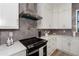 Modern kitchen with black cooktop, stainless steel range hood, and white cabinets at 11 Pinehurst Ct, Rotonda West, FL 33947