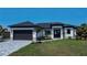 Stunning curb appeal! This new home features a modern design, dark gray garage door, and beautifully landscaped lawn at 11 Pinehurst Ct, Rotonda West, FL 33947