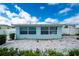 Back of home featuring a paved patio, complemented by well-maintained landscaping and a charming blue exterior at 22062 Marshall Ave, Port Charlotte, FL 33952