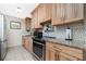 Kitchen featuring stainless steel appliances, granite countertops, natural wood cabinets, and mosaic backsplash at 22062 Marshall Ave, Port Charlotte, FL 33952