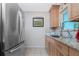 Bright kitchen featuring stainless steel refrigerator, stone countertops, natural wood cabinets and mosaic backsplash at 22062 Marshall Ave, Port Charlotte, FL 33952