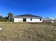 Rear exterior view of a home featuring white siding and a black roof against a blue sky at 26345 Trinilas Dr, Punta Gorda, FL 33983