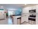 Open-concept kitchen with white cabinets, stainless steel appliances, and tile flooring leading into the living and dining areas at 7168 W Lenox Cir, Punta Gorda, FL 33950