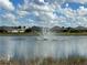 Picturesque view of a serene pond with a fountain and neighborhood homes in the background at 7168 W Lenox Cir, Punta Gorda, FL 33950