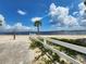 Peaceful beachfront view with white fence, palm tree, and calm water at 1286 Hillcrest Nw Ave, Port Charlotte, FL 33948