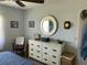 Bedroom with dresser, chair, and large round mirror at 26470 Rampart Blvd # 123, Punta Gorda, FL 33983