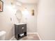 Small, updated half bathroom with a dark vanity and oval mirror at 3621 Whippoorwill Blvd, Punta Gorda, FL 33950