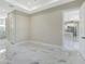 An airy bedroom features marble floors, tray ceiling, and an open entry to the kitchen at 212 Fairway Rd, Rotonda West, FL 33947