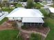 Property showcases a metal roof, screened porch, and well-manicured landscaping at 834 Forest Hill Nw Ln, Port Charlotte, FL 33948