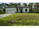 Single-story home with attached garage and grassy lawn at 13460 Tolman Ave, Port Charlotte, FL 33953