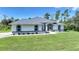 Charming home featuring blue trim accents, a well-manicured lawn and a screened in entry at 17183 Carson Ave, Port Charlotte, FL 33948