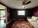 Cozy bedroom with dark red accent walls, a ceiling fan, a window, and an area rug with botanical accents at 1405 Dorchester St, Port Charlotte, FL 33952