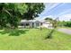 Single-story home with a teal front door, metal roof, and spacious lawn at 8516 Riverside Dr, Punta Gorda, FL 33982