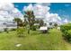 Expansive backyard with lush green grass, mature palm trees, and a charming chicken coop at 7456 Jennifer Dr, Port Charlotte, FL 33981