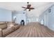 Expansive living room with wood-look flooring, a ceiling fan, and seamless access to the kitchen at 7456 Jennifer Dr, Port Charlotte, FL 33981