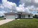 One-story home with a white and gray exterior, two-car garage, and a well-maintained lawn at 16216 Minorca Dr, Punta Gorda, FL 33955
