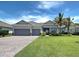 Well-manicured front yard and home exterior with a two-car garage, large driveway, and mature landscaping at 15240 Spanish Point Dr, Port Charlotte, FL 33981