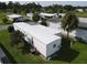 Aerial view of single-wide home with surrounding homes and lush landscaping at 5417 Holiday Park Blvd, North Port, FL 34287