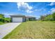 Charming single-story home with a gray exterior, white garage door, and landscaped yard at 725 Essex Ave, Port Charlotte, FL 33948