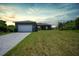 Single-story home with a gray exterior, white garage door, and a paved driveway at 725 Essex Ave, Port Charlotte, FL 33948