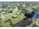 Aerial view of a residential neighborhood near a canal with mature trees and green lawns at 3107 Easy St, Port Charlotte, FL 33952