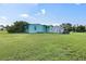 Exterior view of property with green grass, storage shed, propane tank, and lush vegetation at 3107 Easy St, Port Charlotte, FL 33952