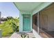 Charming home featuring a turquoise front door and a spacious, sunlit porch with tropical landscaping at 3107 Easy St, Port Charlotte, FL 33952