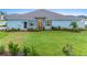 Single-story home boasting a green lawn and colorful landscaping complemented by a stone accent wall and light blue paint at 1781 W Palms Dr, Port Charlotte, FL 33953