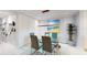 Modern glass dining table with four chairs, stylish light fixture, and wall art at 25188 Marion Ave # D101, Punta Gorda, FL 33950