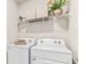 Functional laundry room featuring modern white washer and dryer and a wire storage shelf above at 16429 Bridle Ridge St, Port Charlotte, FL 33953