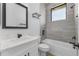 Modern bathroom with tub, shower, gray tiled walls, and sink with marble countertop at 24051 Pyramid Way, Punta Gorda, FL 33955