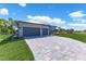 Modern home features an expansive driveway and a lush lawn, enhanced by tropical landscaping at 24051 Pyramid Way, Punta Gorda, FL 33955