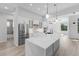 Bright kitchen with stainless steel appliances, white cabinetry, island with marble countertop, and wood flooring at 24051 Pyramid Way, Punta Gorda, FL 33955