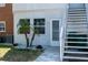 Exterior view of the residence featuring stairs leading up and a well-maintained yard with lovely palm trees at 4158 Tamiami Trl # U6, Port Charlotte, FL 33952