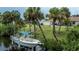 Private backyard with lush greenery, tall palm trees, a private boat dock and home access at 2256 Auburn Blvd, Port Charlotte, FL 33948